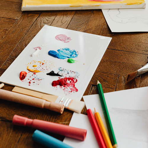 paper with paint on wooden floor surrounded by art supplies